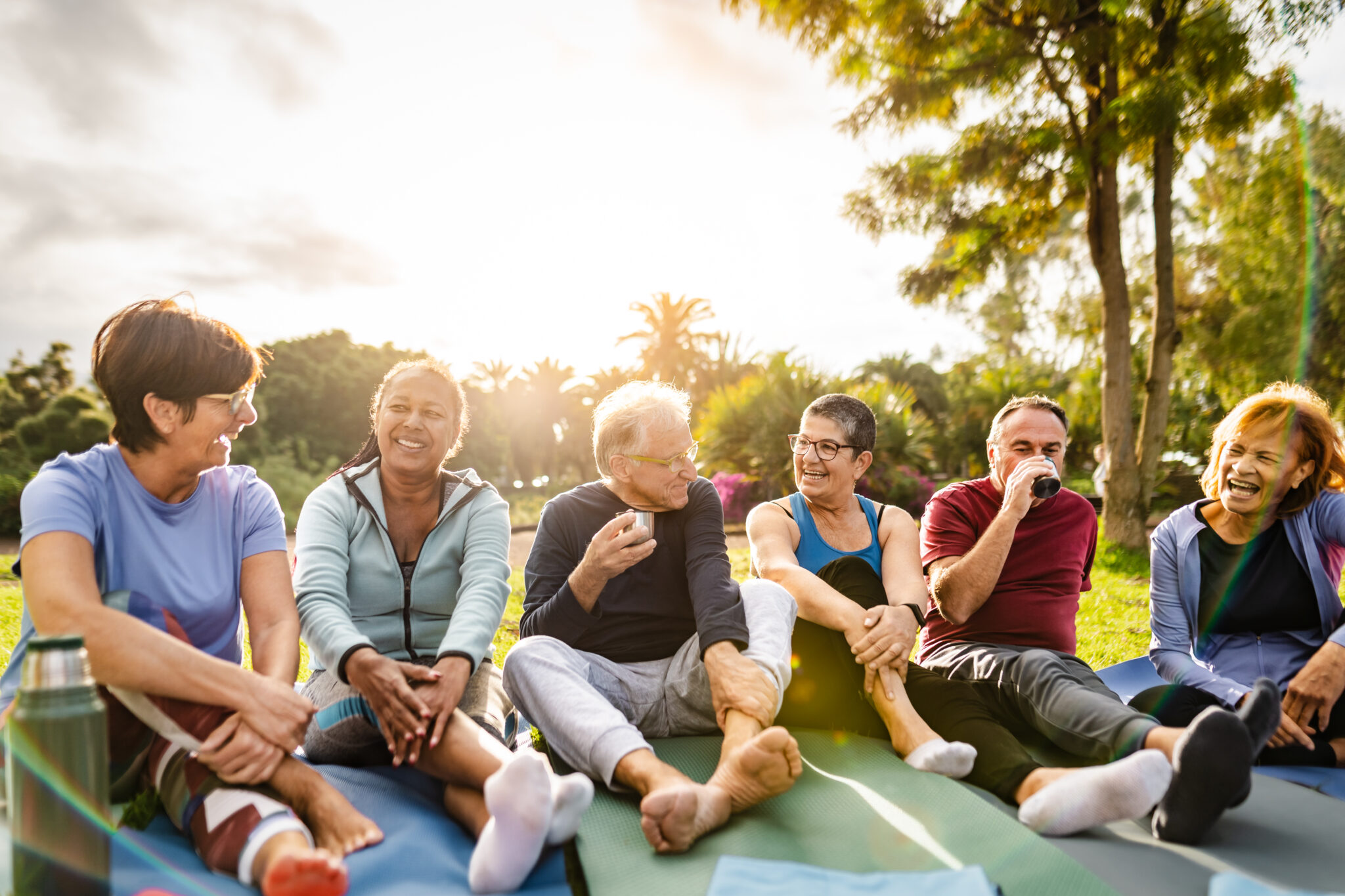 Happy multiracial senior friends drinking a tea after workout activities in a park Happy multiracial senior friends drinking a tea after workout activities in a park