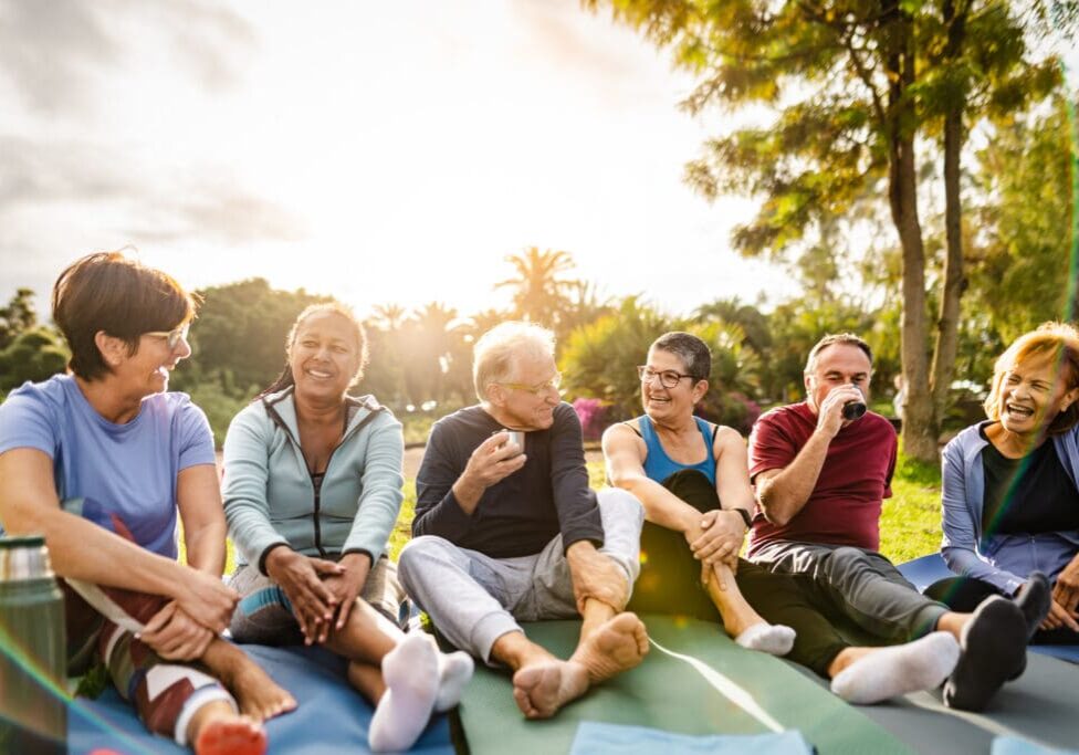 Happy multiracial senior friends drinking a tea after workout activities in a park